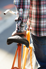 Image showing Hands, person and push bike in city to travel on eco friendly transport outdoor, commute or walk. Cycling, back or bicycle in urban town, street or road for journey with rear view of seat on sidewalk