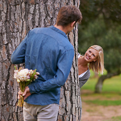 Image showing Couple, park and love for valentines day with flower in romance, boyfriend for girlfriend. Romantic, outdoor and date to play with hide and seek for bonding, happiness and relax for wellness