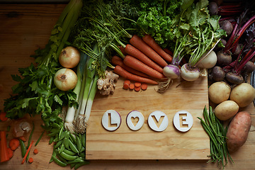 Image showing Food, chopping board and message for love, nutrition and cooking for wellbeing or eating. Home, above and vegetables for diet, health and vitamins in kitchen for vegan, vitality and top view