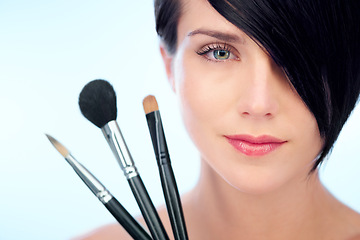 Image showing Woman, portrait and makeup brushes in studio with beauty, cosmetic tools or product application for skincare. Model, face and confidence with skin wellness, cosmetology or grooming on blue background