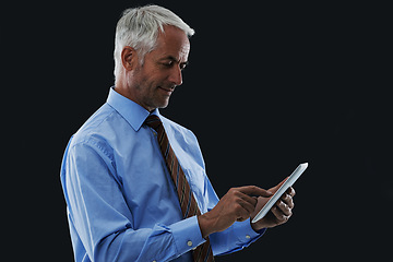 Image showing Businessman, tablet and typing in studio for research, communication or networking with clients online. Male CEO, technology and scrolling for information, planning or working on black background