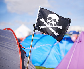 Image showing Pirate flag, tent and camping at festival outdoor in summer for party, event or celebration closeup. Skull, crossbones or jolly roger in nature for performance, entertainment or adventure with crowd