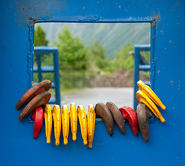 Image showing Colorful hooks hanging on a blue metal frame outdoors