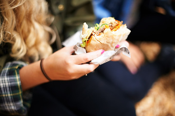 Image showing Woman, hands and burger with hungry for food, nutrition and take away on holiday in outdoor. Person, eating and satisfaction with protein roll in hand, closeup or foodie outside on vacation leisure