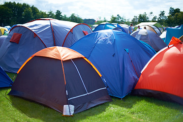 Image showing Group, colourful and camping tents in nature outside of a music festival campsite. Row of canopies placed on ground at musical concert, entertainment event and carnival celebration outdoor on grass