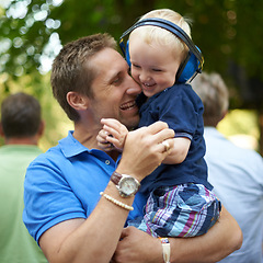 Image showing Father, hug and baby at outdoor festival for family together, happiness and headphones for loud sound. Man, kid and love for child, playful and laugh at music concert in Hollywood for summer holiday
