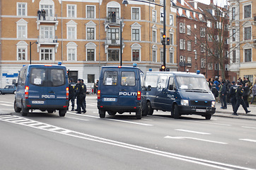 Image showing Police, van and street with crowd, safety or protection service for public with justice in city. Vehicle, law enforcement and outdoor for danger, arrest and transportation on urban road in Copenhagen