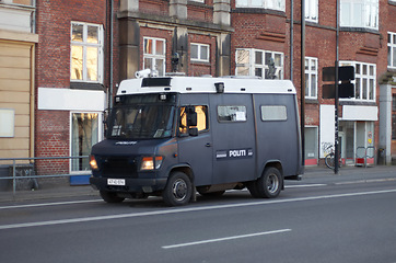 Image showing Armored van, police and transport in street for safety, justice and patrol for protection in city. Vehicle, urban road and driving for public service to stop crime in metro by buildings in Copenhagen