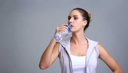 Image showing Woman, fitness and drinking water for hydration or natural sustainability on a gray studio background. Face of thirsty female person or athlete with mineral drink in rest, break or recovery on mockup