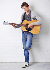 Image showing Man in portrait, guitar and musician with creativity and music, acoustic for entertainment and performance on wall background. Busker, artist and musical instrument for art, track or song with talent