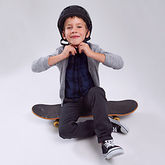 Image showing Smile, skateboard and portrait of child in studio with helmet for safety learning skating. Happy, security and young boy kid with headgear for practicing fun hobby or activity by gray background.