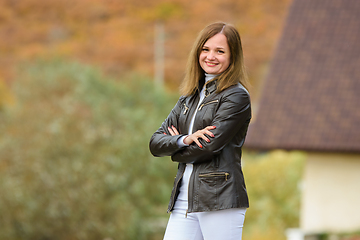 Image showing Portrait of a young beautiful girl in casual clothes against the background of a blurred autumn forest