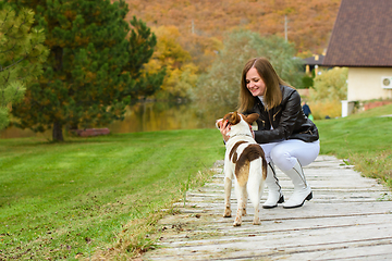 Image showing A young beautiful girl pets a dog against the backdrop of a beautiful landscape