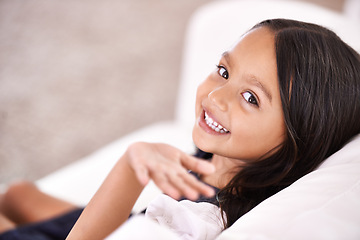 Image showing Happy, wave and portrait of child on sofa for playful, fun and rest on weekend in living room. Smile, childhood and face of young girl alone on couch for relaxing, comfortable and free time in home