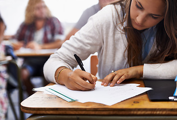 Image showing University, classroom and woman writing exam at desk for education, knowledge and opportunity. College, learning and student with paper for test, assessment and studying with books, notes or report.