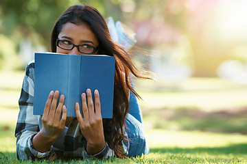 Image showing Woman, student and lying with book on green grass for literature, studying or story in nature. Female person, nerd or young geek with notebook for reading, education or secret to future at the park
