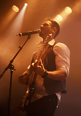 Image showing Concert, singer and guitar with man on stage for music, performance and rock show. Event, spotlight and energy with male musician playing instrument at festival club for rave, disco and celebration