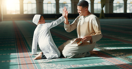 Image showing Muslim, high five in a mosque and a father with his son to study the quran for faith, belief or religion together. Family, kids and ramadan with a man teaching his boy child about islamic success