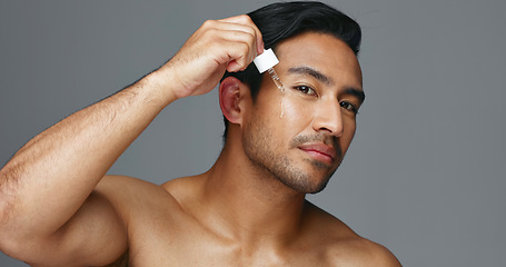 Image showing Face, pipette and Asian man with skincare, oil and dermatology on a grey studio background. Portrait, Japanese person and model with wellness, treatment and grooming product with aesthetic and glow