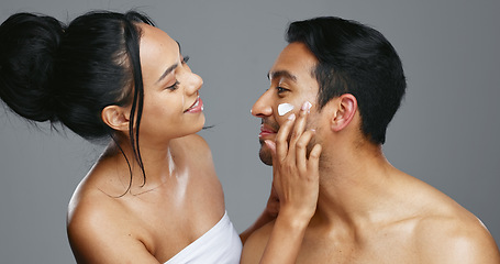 Image showing Couple, smile and love for skincare, happy and portrait with moisturizer in studio by gray background. Happy people, dermatology and hug for cosmetics, hydration and creme or care for skin treatment