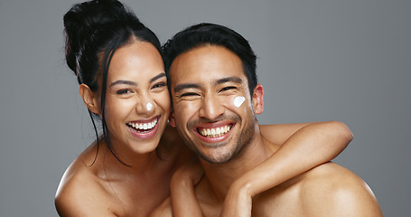 Image showing Couple, smile and love for skincare, care and portrait with moisturizer in studio by gray background. Happy people, dermatology and hug for cosmetics, hydration and creme or love for skin treatment