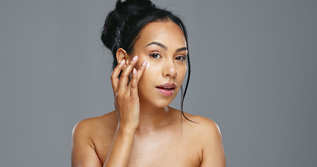 Image showing Face, skincare and happy woman with cream in studio isolated on a gray background. Portrait, natural beauty and model apply moisturizer, cosmetics and product for wellness, dermatology and health