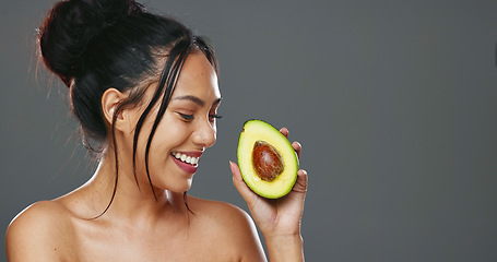 Image showing Woman, avocado and beauty in studio for health, diet or smile on face for skincare by background. Girl, model or happy for fruit, nutrition choice or vegan food for wellness, natural glow or portrait