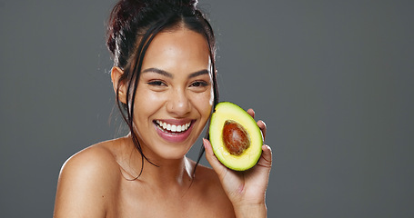 Image showing Woman, avocado and beauty in studio for health, diet or smile on face for skincare by background. Girl, model or happy for fruit, nutrition choice or vegan food for wellness, natural glow or portrait