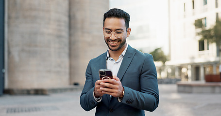 Image showing Asian businessman, mobile message and walking in city, view and confident professional in career by office buildings. Young lawyer, chat and smartphone for connection and technology in cbd in town