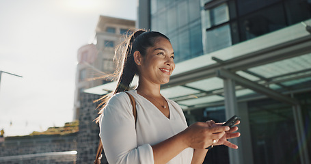 Image showing Phone, smile and wind with businesswoman in city, walking on street or sidewalk for morning work commute. Contact, mobile or social media with happy young employee in urban town for travel journey