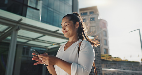 Image showing Phone, smile and wind with businesswoman in city, walking on street or sidewalk for morning work commute. Contact, mobile or social media with happy young employee in urban town for travel journey