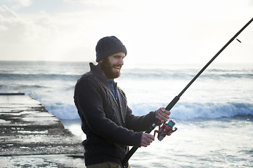 Image showing Fishing, smile and travel with man at beach for adventure, holiday and hobby break. Sunset, calm and patience with male fisherman and casting rod pole in nature for recreation, view and vacation