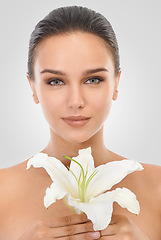 Image showing Makeup, floral and portrait of woman in studio with glamour, glow and cosmetic face routine. Beauty, confident and young female person with flower plant for facial cosmetology by gray background.