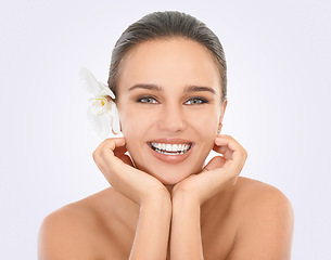 Image showing Girl, portrait and orchid with glow for skincare in studio, beauty and natural makeup for blossom. Woman, plant and white background, closeup and hands on face with cosmetics dermatology for wellness