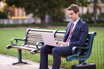 Image showing Businessman, laptop and typing on park bench in nature for trading, checking email or outdoor networking. Man or trader in business suit on computer for communication or finance on outside furniture