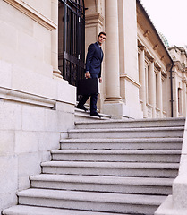 Image showing Business, briefcase and man on stairs outside law firm in city with evening commute, checking sidewalk and court building. Businessman, lawyer or attorney on outdoor steps with bag for urban travel.