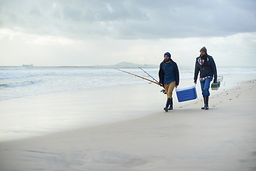 Image showing Friends, fishing and men walking on beach together with cooler, tackle box and holiday mockup space. Ocean, fisherman and people with rods, bait and tools at waves on winter morning vacation at sea.