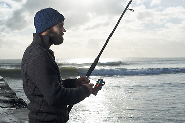 Image showing Night, fishing and man at a beach with pole for water hobby, recreation or stress relief vacation in nature. Casting, rod and male fisherman at sea for travel, adventure or fisher sports in Cape Town