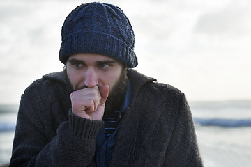 Image showing Winter, breathing and beach with man, thinking and cold weather with waves and freezing. Person, ocean and guy with wool jersey and cap with early morning activity and nature with vacation and travel