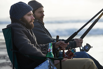 Image showing Friends, men and fishing on beach in nature with rod, alcohol and relax on vacation, holiday or travel. Friendship, people and bonding in morning with overcast, sky and waves for activity or hobby
