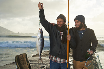 Image showing Happy, people and fishing at ocean with pride for catch of tuna on holiday, travel or vacation. Fisherman, friends and smile holding fish and net in hand on adventure in nature with waves at sea