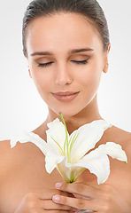 Image showing Cosmetic, flower and woman in studio with beauty, glow and natural makeup face routine. Organic, confident and young female person with floral plant for facial cosmetology by white background.