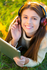 Image showing Woman, headphones and tablet in portrait on grass, streaming radio and podcast in outdoors. Happy female person, nature and internet for classical playlist on weekend, calm and peaceful song on lawn
