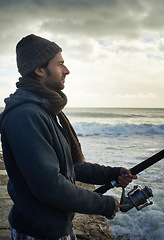 Image showing Fishing, relax and travel with man at beach for adventure, holiday and hobby break. Sunset, calm and patience with male fisherman and casting rod pole in nature for recreation, view and vacation