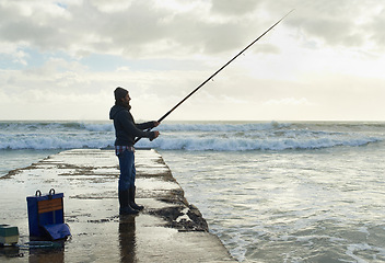 Image showing Fishing, fisherman and man on pier by sea with rod, reel and equipment to catch fish for hobby. Nature, sports and person cast a line for recreation or adventure on holiday, vacation and weekend