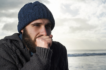 Image showing Winter, breathing and ocean with man, thinking and cold weather with waves and freezing. Person, beach or guy with wool jersey or cap with early morning activity or nature with holiday, travel or sky