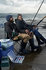 Image showing Sea, rod for fishing and men outdoor in winter, leisure activity at beach or harbor with friends in nature for seafood. Travel, ocean and waves with happy fisherman, recreation or hobby in the cold