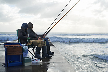 Image showing Ocean, fishing rod and men outdoor in winter, leisure activity at beach or harbor with friends in nature for seafood. Travel, seascape and waves with fisherman, recreation or hobby in the cold