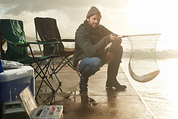 Image showing Portrait, net and beach with man, fish and hobby with equipment, sunshine and weekend break. Person, ocean and guy with tools for activity and happiness with waves, shore and seaside with lens flare