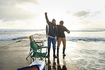 Image showing Happy, portrait and people fishing at ocean with pride for tuna catch on pier at sunset. Fisherman, friends and smile holding fish in hand with success in nature at sea on holiday or vacation